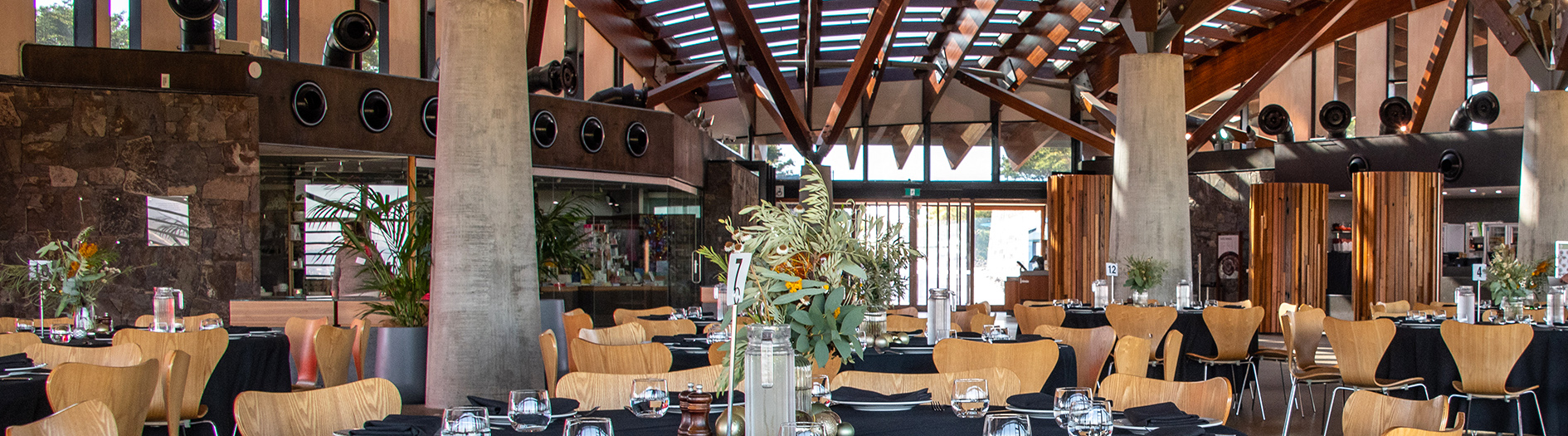 The interior of the Visitors Centre with tables and chairs laid out for a function, with the tables decorated with native floral bouquets