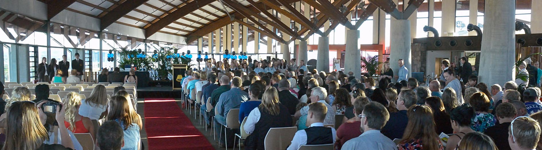 Graduation ceremony with red carpet down the centre and people seated either side.