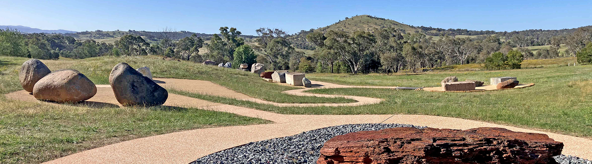 A large collection of colourful boulders displayed outside, with a sealed footpath meandering between them