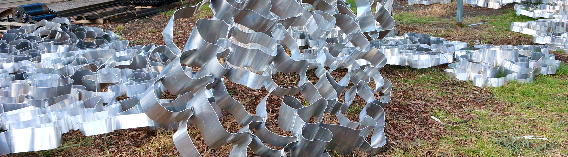 Close up of the twisted metal detail of Hannahah Quinliven's piece 'Drawing Breath' laid on the grass outside her studio.