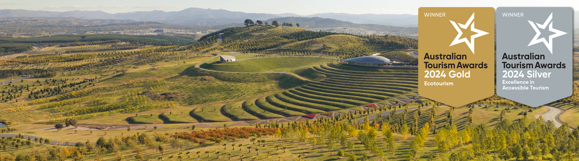 Aerial view of the Arboretum showing the Visitors Centre, Central Valley Gardens and the view across Canberra. Overlayed are the Tourism Awards badges.