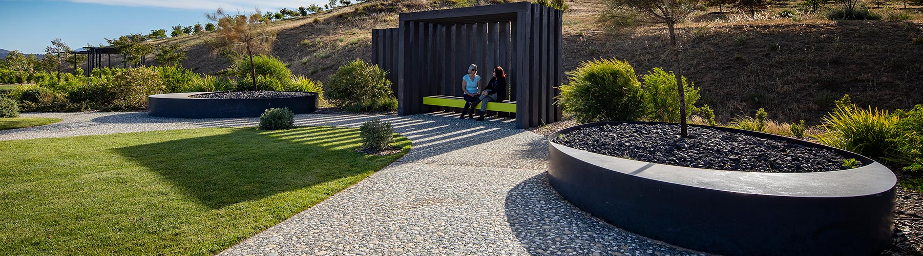 two people sitting in shaded shelter on a sunny day
