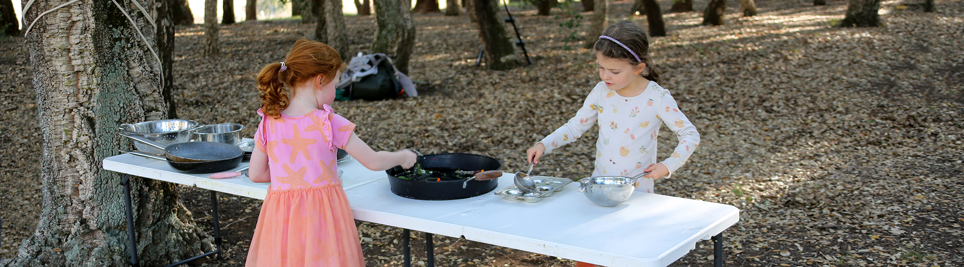 Two girls playing in the Nature Kitchen in the Cork Oak Forest.