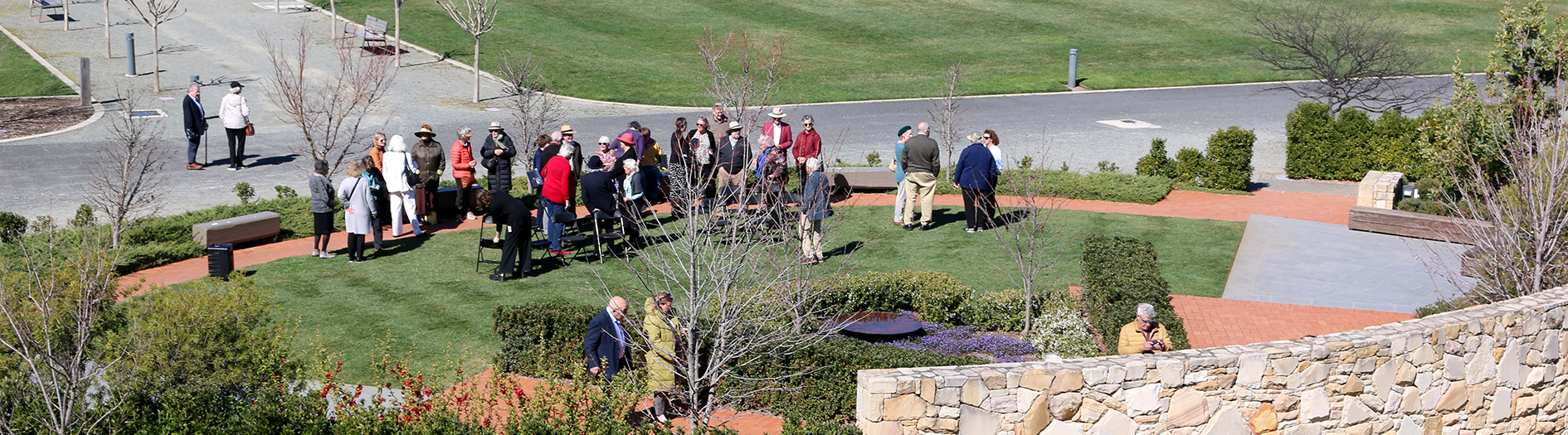 A distant view showing the circular landscaped gardens and the guests and the event milling around