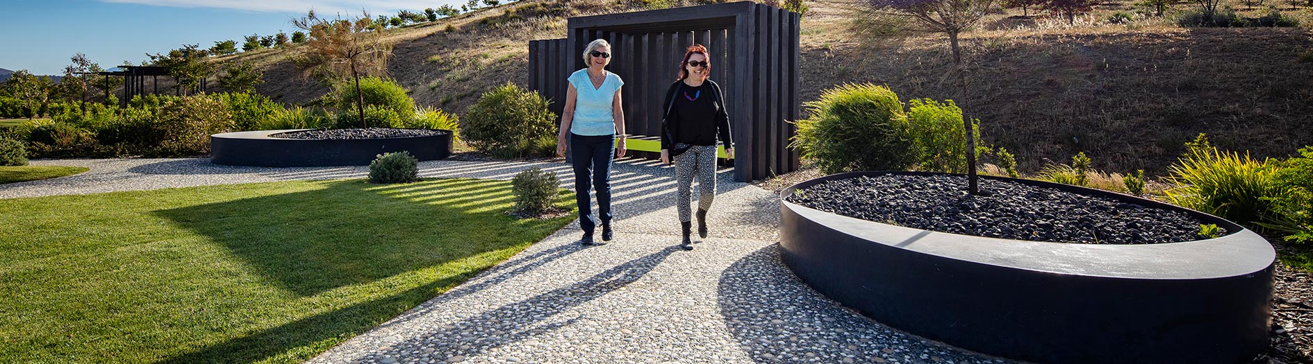 two women walking along garden path