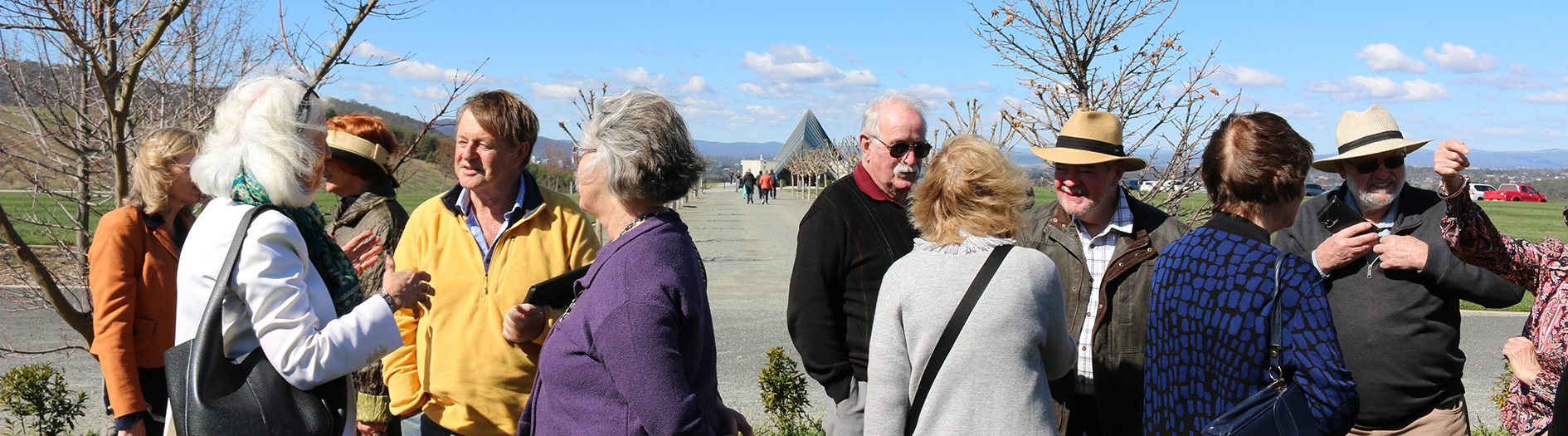 A group of adults mingle after the event, on a sunny but windy day