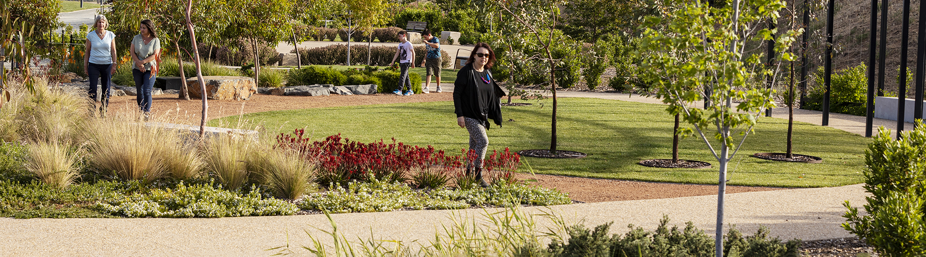 Photo of woman walking on gravel paths through garden