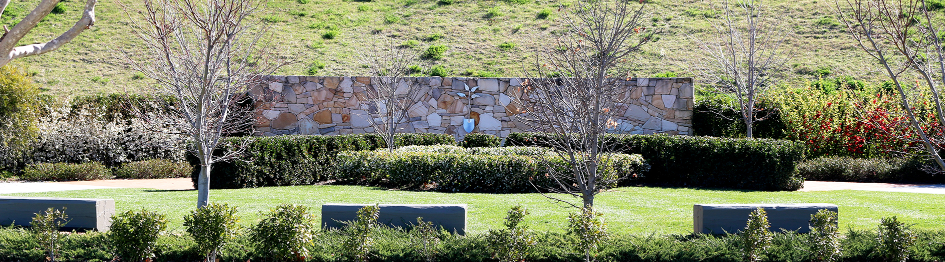 A distant perspective of the landscaped gardens with manicured hedges, lawns and a stone feature wall