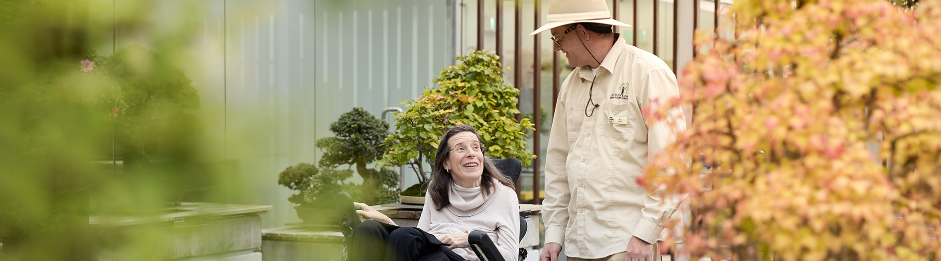 Bonsai Volunteer providing a guided tour to a lady in a powered chair