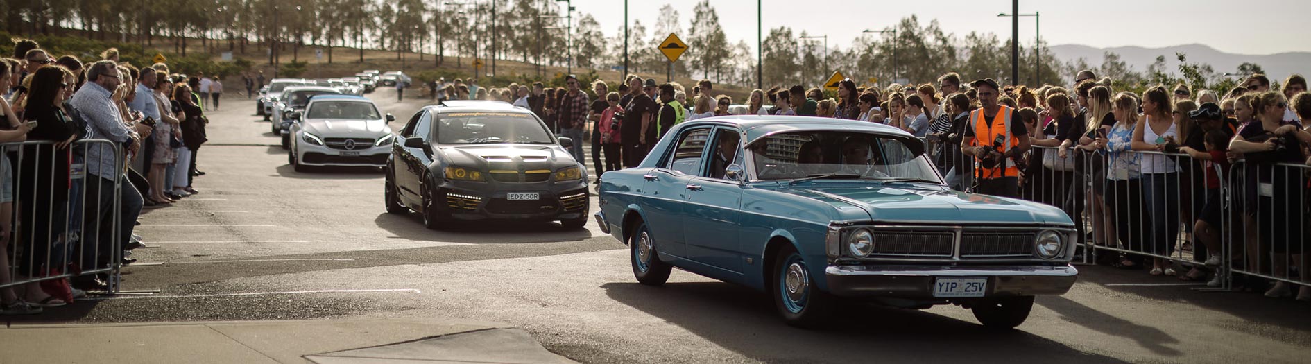Arrival cars lined up with spectators either side behind safety barriers.