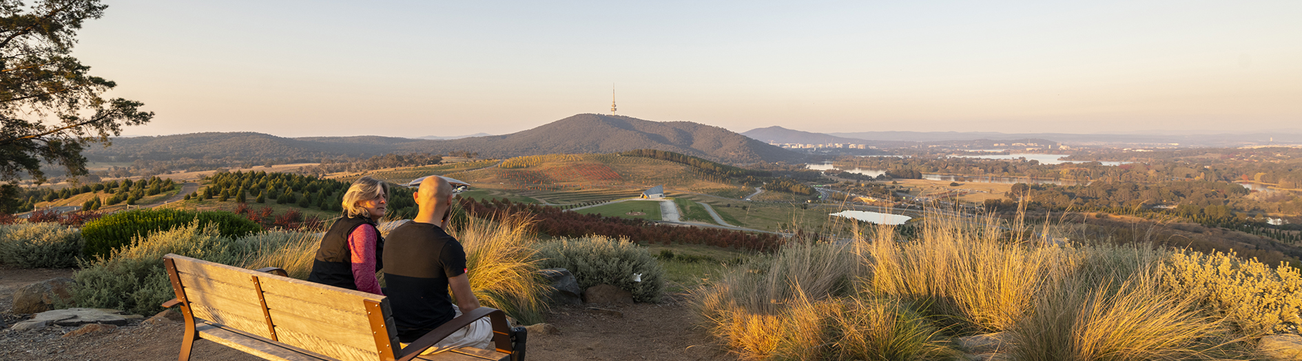 Two people sitting on a bench seat admiring the view at sunset
